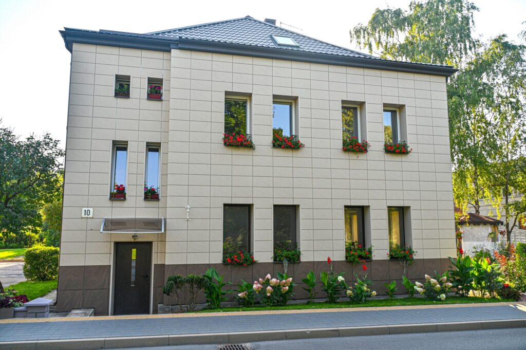 Keliaujantieji A. Jakšto gatve nejučia sulėtina žingsnį ties 10-uoju numeriu pažymėtu daugiabučiu. Akį patraukia kaskados nuo palangių svyrančių žiedų, namą supantys ištaigūs gėlynai.